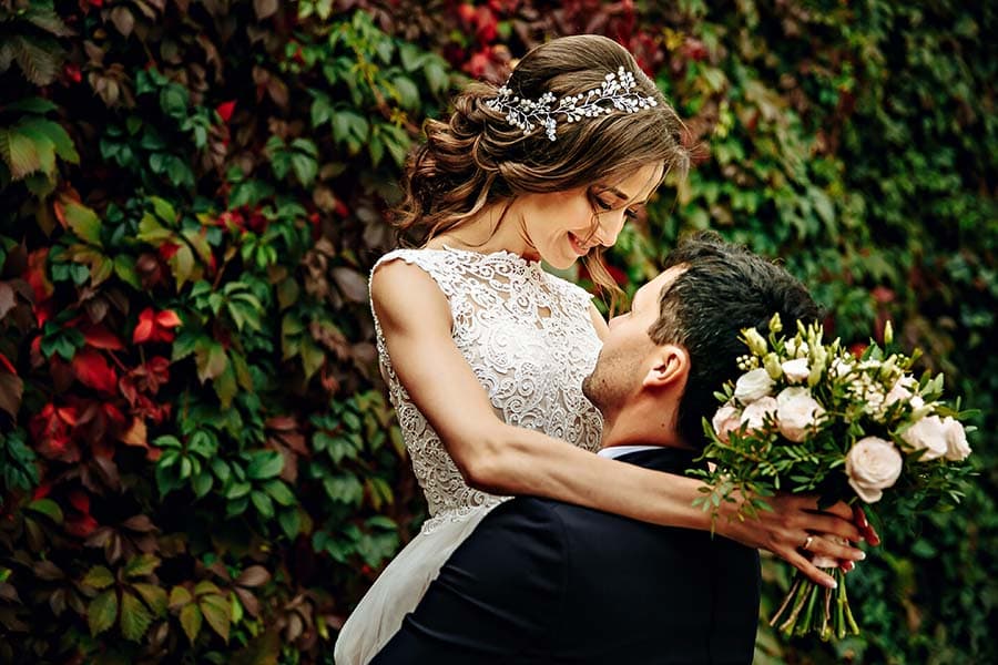 A joyful couple celebrates their wedding against a backdrop of vibrant greenery.