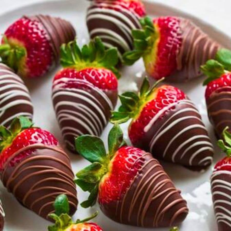A plate of chocolate-covered strawberries drizzled with white chocolate.