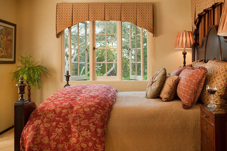 A cozy bedroom featuring a large window, decorative bedding, and soft lighting.