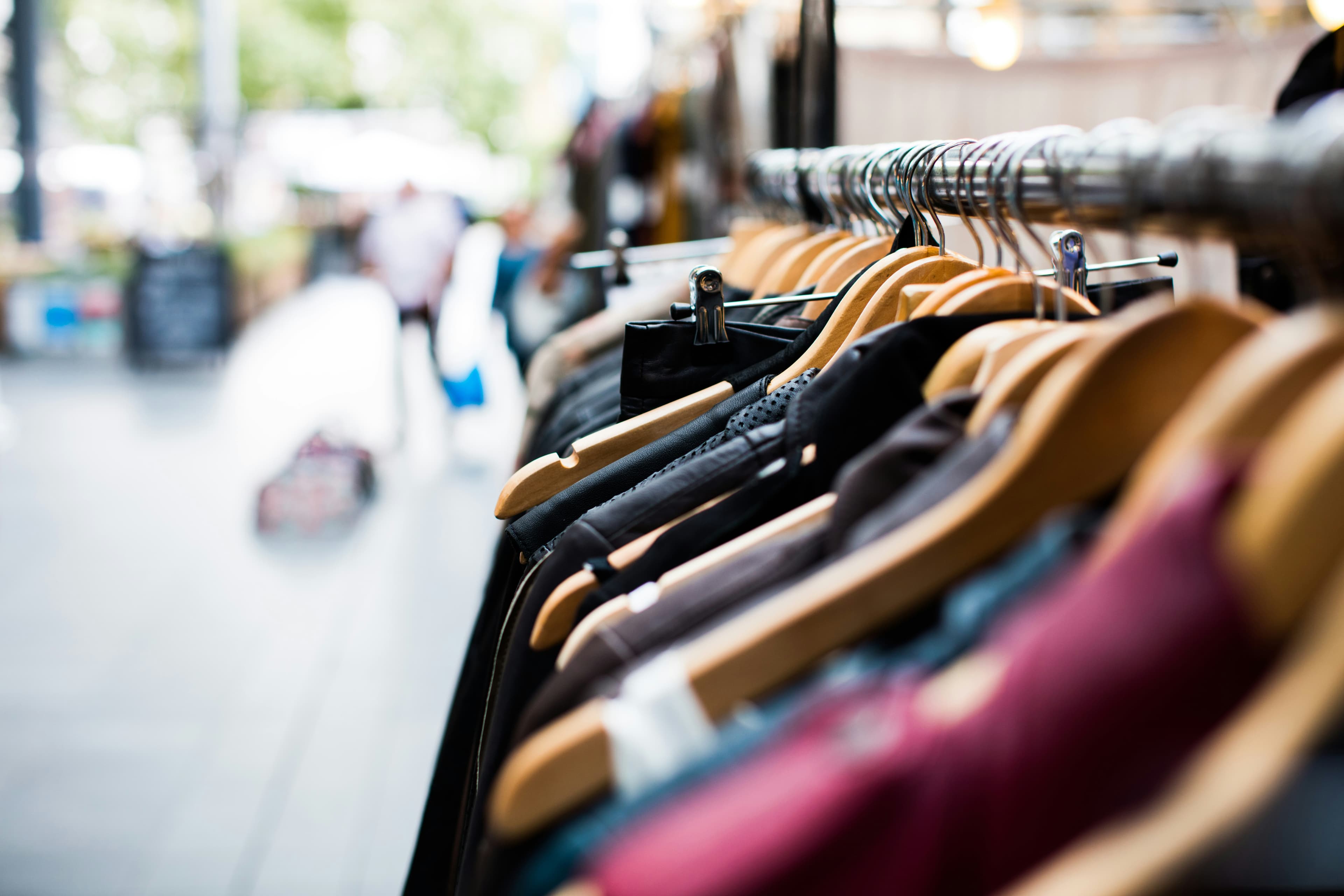 Clothes hanging on a rack in an outdoor market.