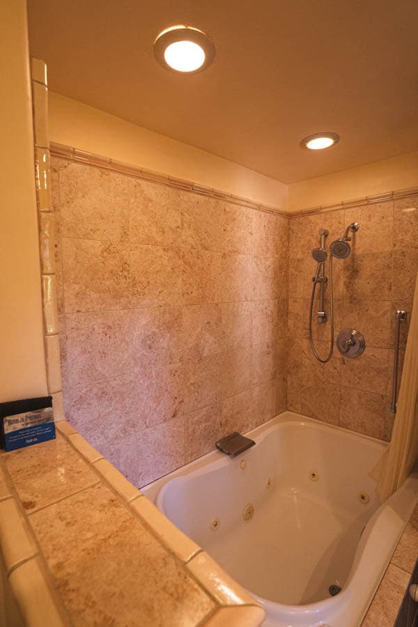 Modern bathroom featuring a jacuzzi tub with a showerhead and marble walls.