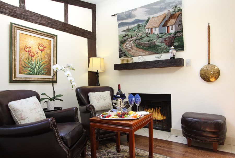 Cozy living room with brown leather chairs, a coffee table with snacks, a fireplace, and decorative artwork.