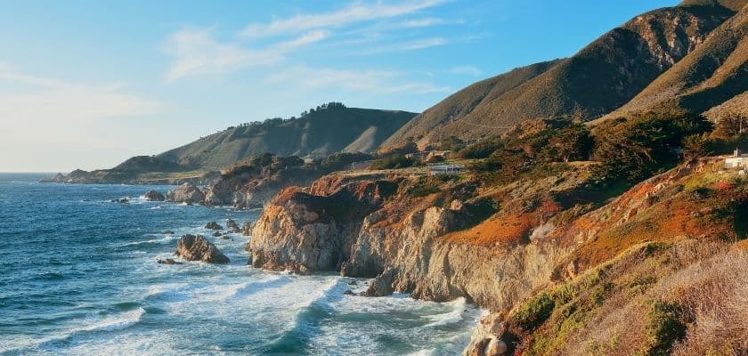 Coastal cliffs meeting the ocean under a clear blue sky.