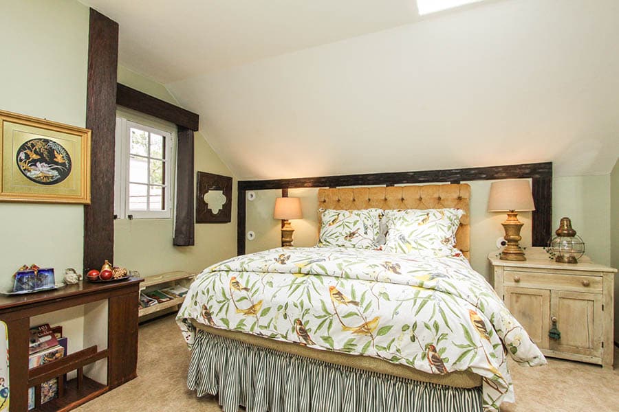 Cozy bedroom with a tufted bed, floral bedding, and warm lighting.