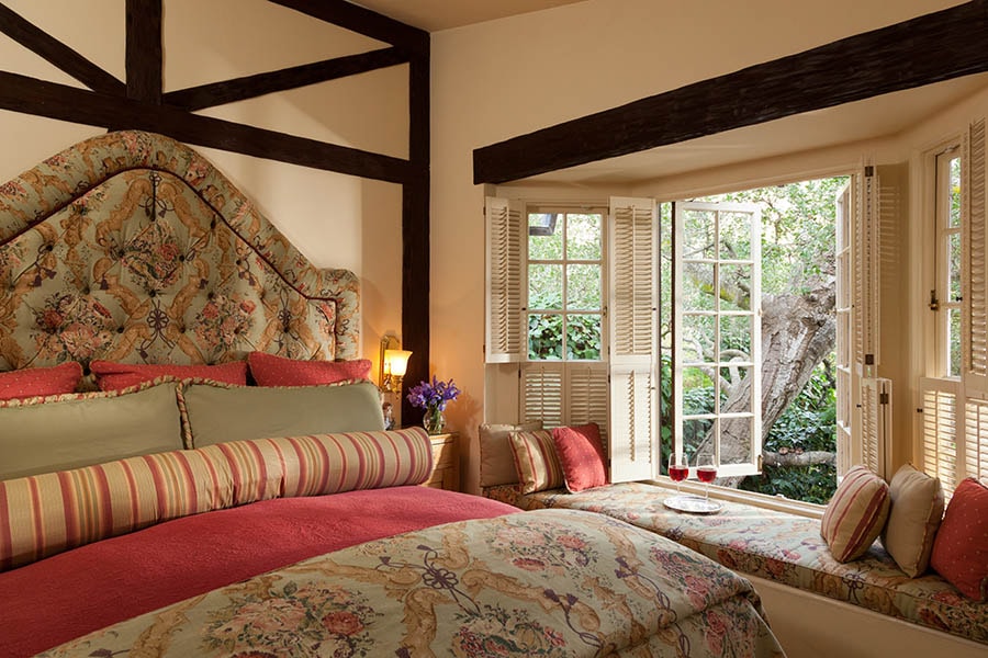 Cozy bedroom featuring a floral bedspread and an open window overlooking a garden.