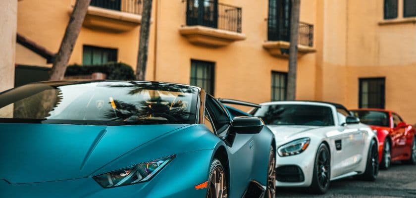Colorful sports cars are parked in a row outside.