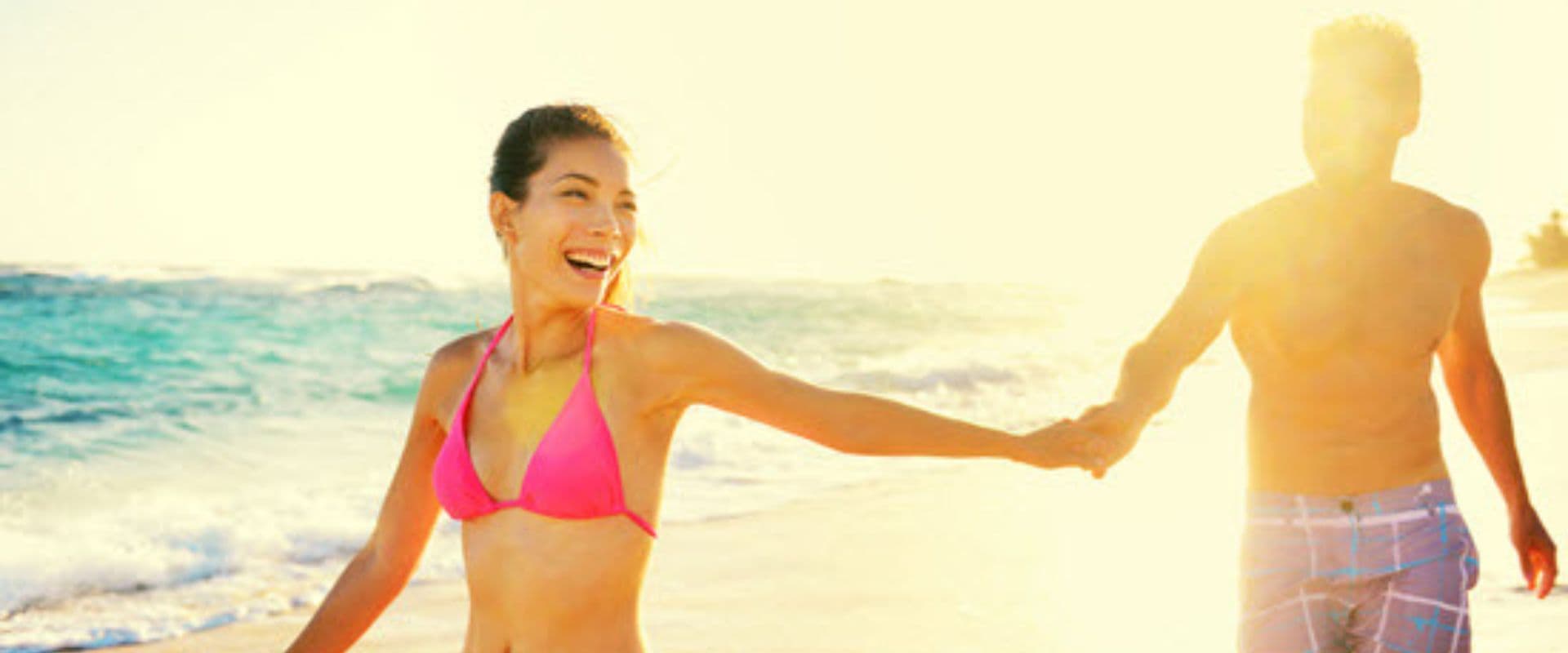 A couple holding hands while walking on the beach