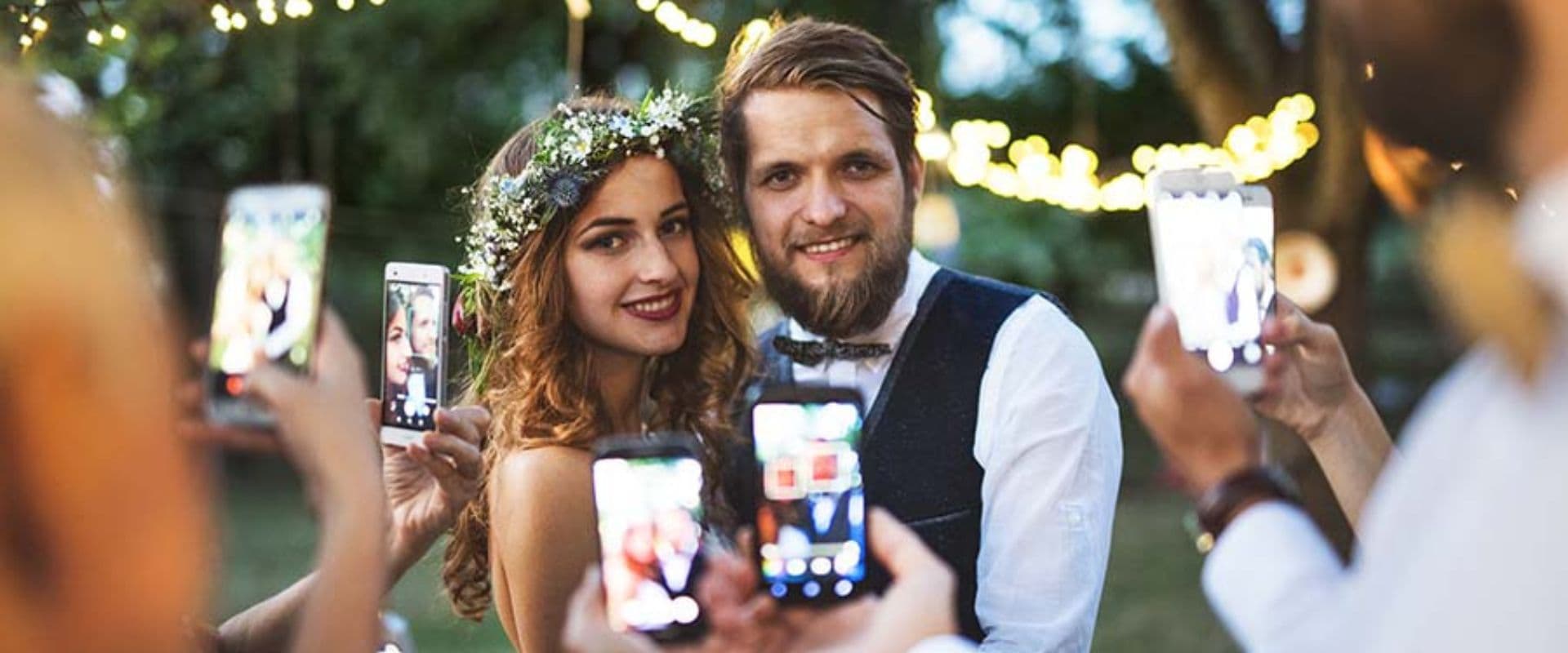 Young couple getting married with friends all holding up cell phones to take pictures
