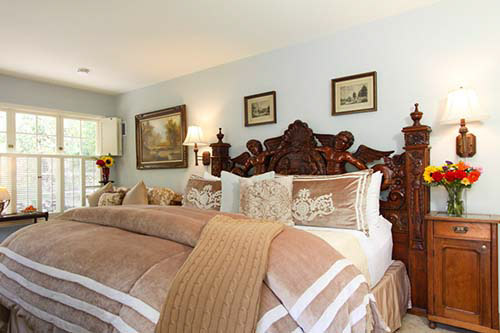 luxury guest room with bed and wood carved headboard